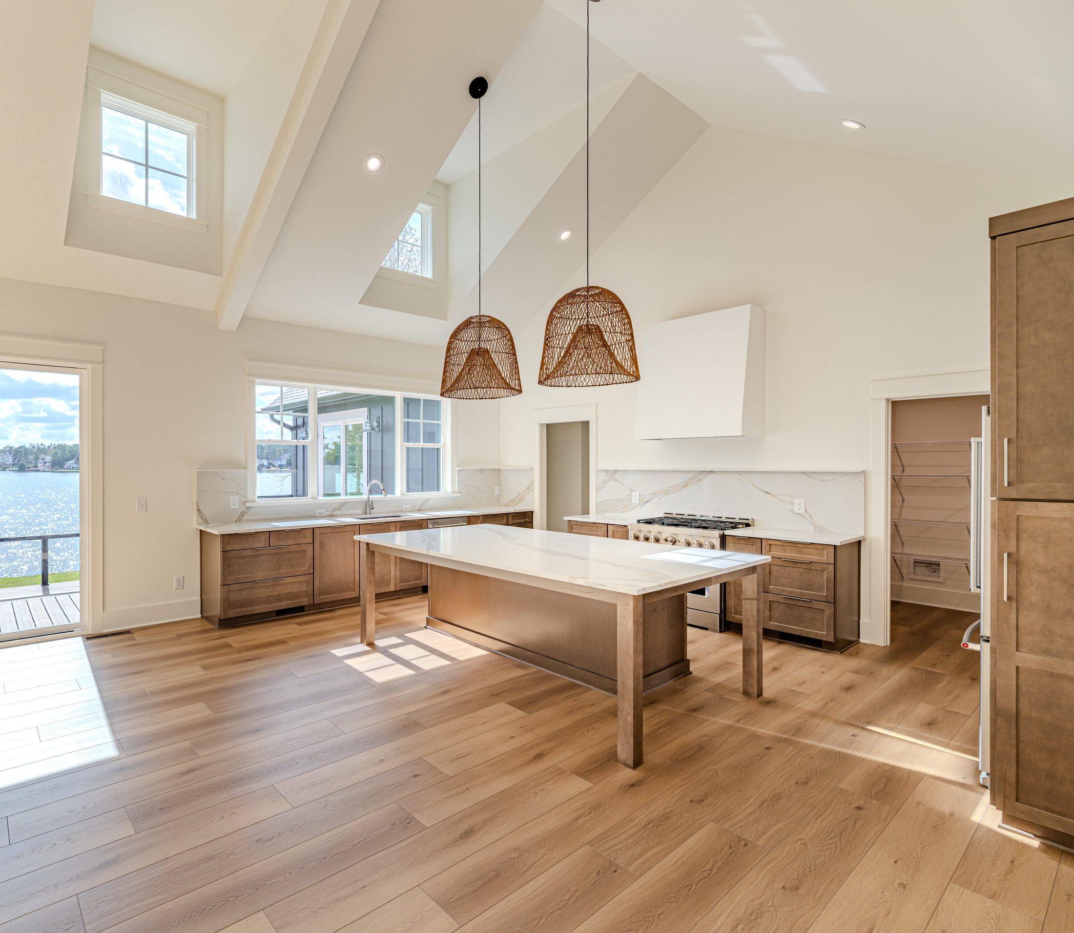 Wide kitchen with wood cabinetry, white island, and vaulted ceiling