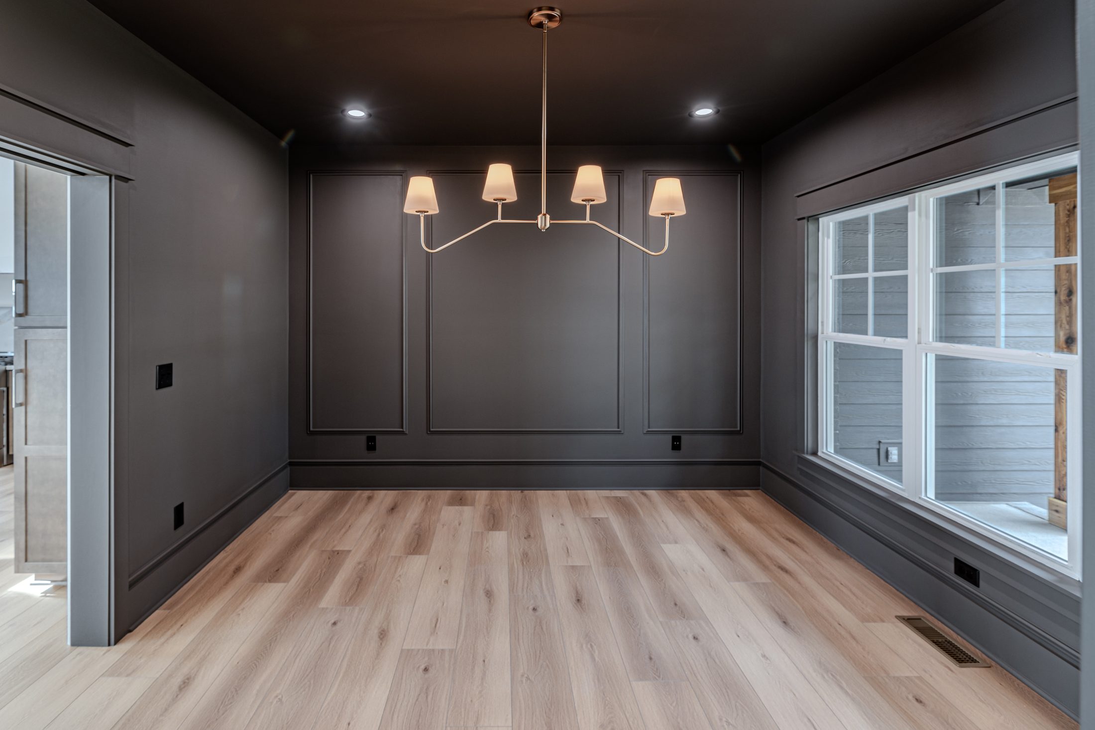 Dark built-in dining room with chandelier and large windows