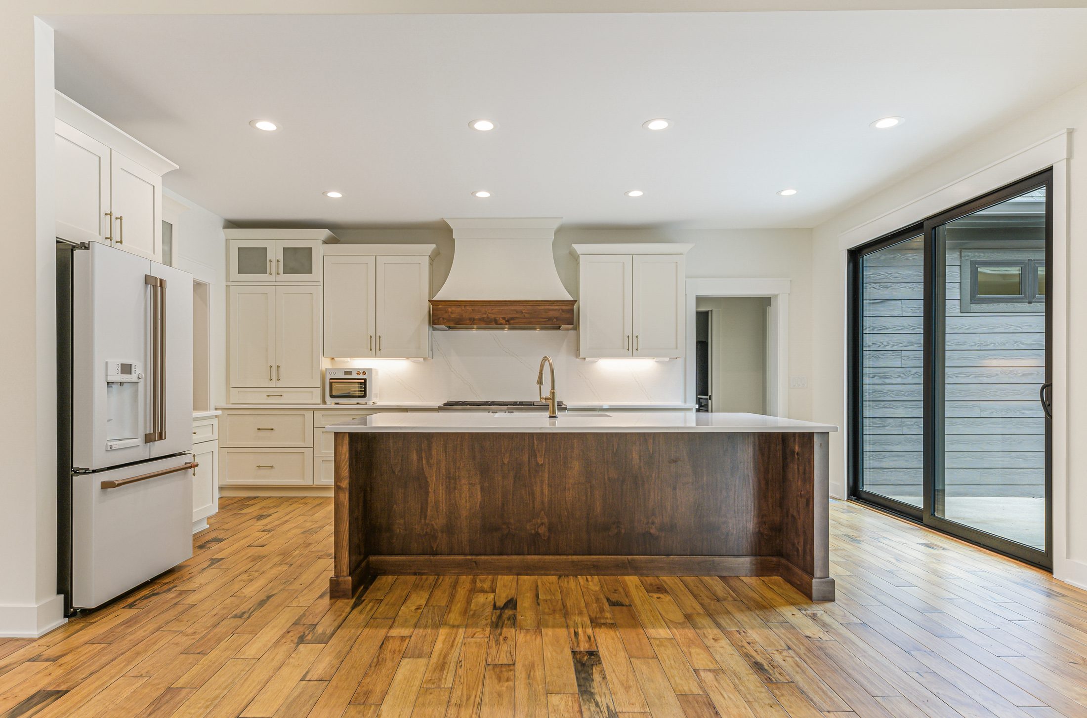 Custom kitchen with white cabinetry and stained wood island in a Arbor Creek custom home in West End