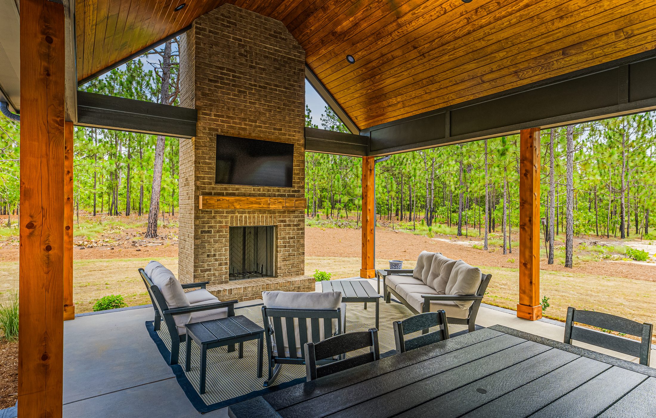 Covered outdoor living area with brick fireplace and timber ceiling